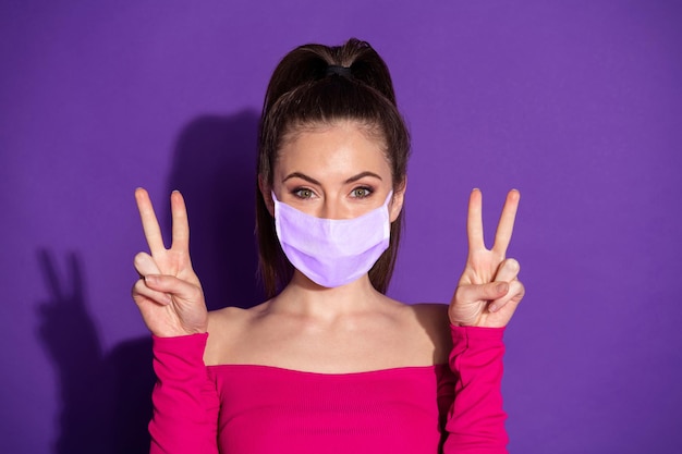 Photo of candid sweet girl two hands make v-sign wear medical respiratory isolated over violet color background