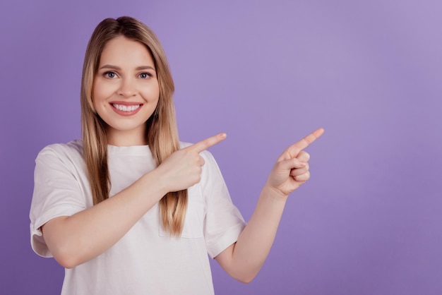 Photo of cheerful promoter lady direct fingers empty space wear casual clothes on purple background