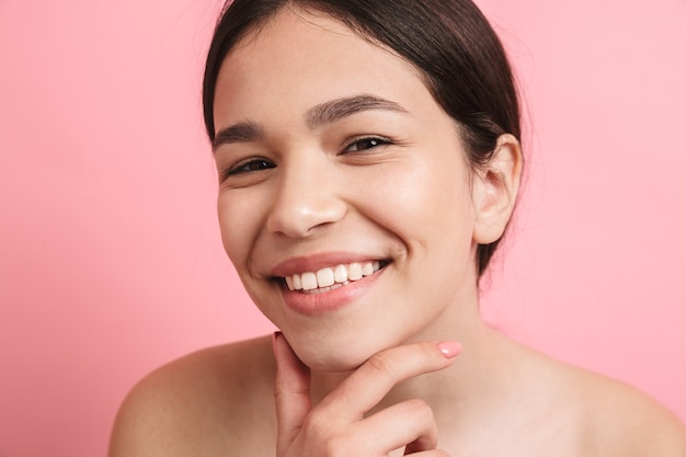 Photo closeup of joyful shirtless girl with dark hair laughing and looking at front isolated over pink wall