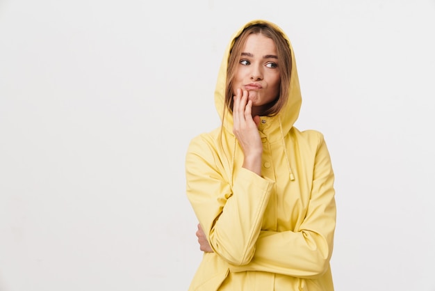 Photo of confused caucasian woman in raincoat posing and looking aside 