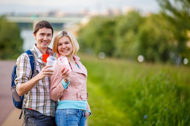 Photo of couple - man and woman with milkshakes in park at summer