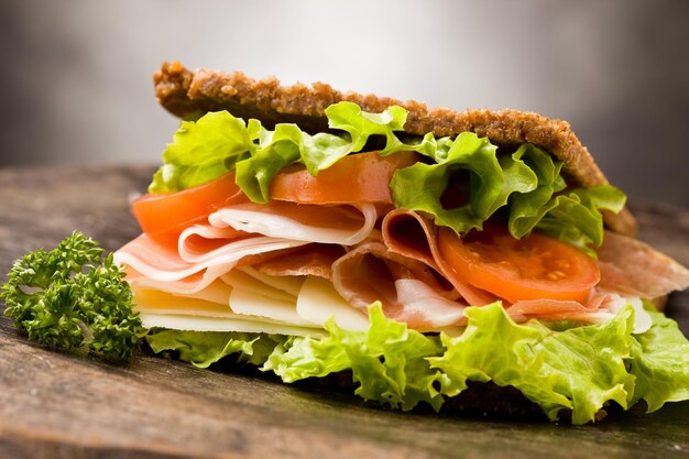 photo of delicious sandwich with smoked bacon and cheese on wooden table