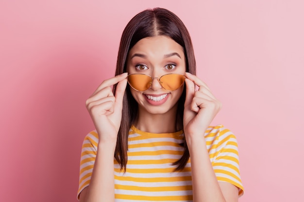 Photo of excited adorable girlish lady adjust sunglass look camera white beaming smile on pink background