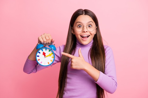 Photo of excited little kid girl point index finger clock wear purple jumper isolated over pastel color background