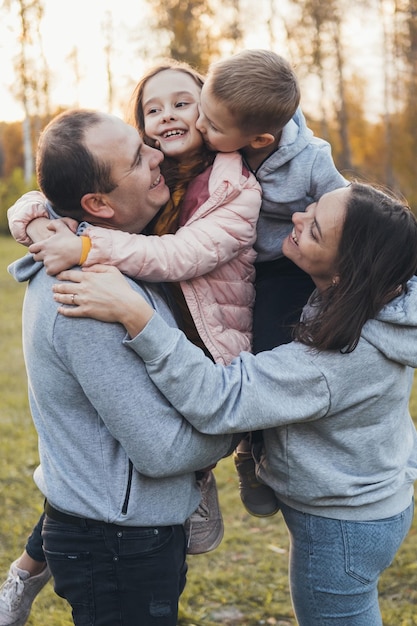 Photo of a family standing together in the park posing while looking at each other happy people