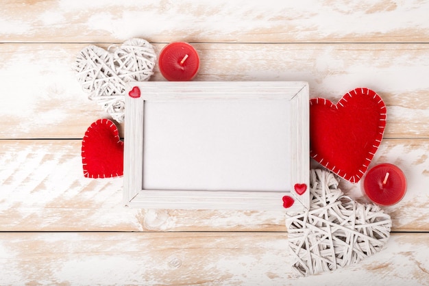 Photo frame between Valentines day romantic decoration with heart and candle on a white wooden table