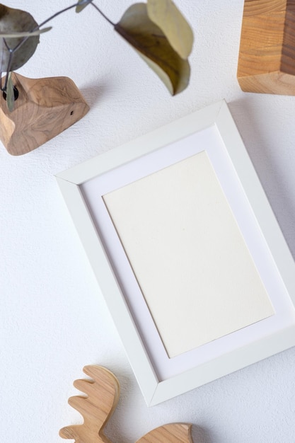 Photo frame with eucalyptus branch in wood vase and wood toy on white background