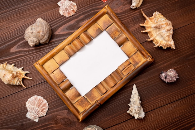 Photo frame with seashells on wooden surface