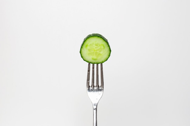 Photo of a fresh cucumber on a fork isolated on a white background