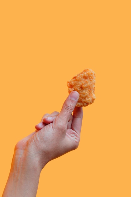 Photo fried chicken nuggets in female hand on yellow background