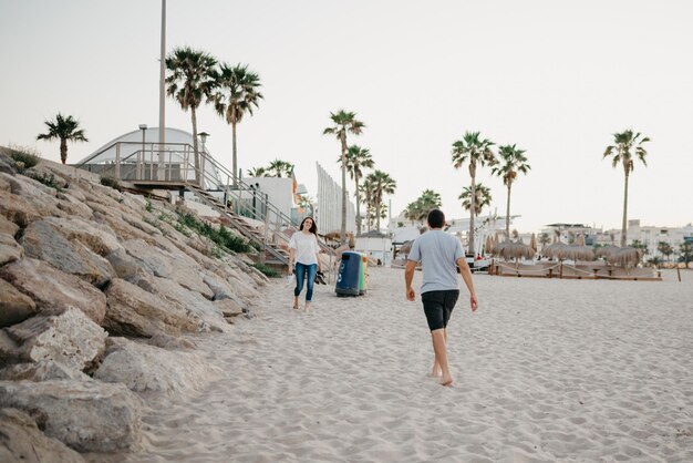 A photo from behind a man who is running to his girlfriend near the breakwater