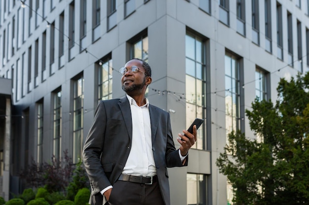 Photo from below portrait of an africanamerican businessman standing in a suit outside an office