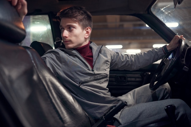 Photo from side of man driver looking back while sitting in car