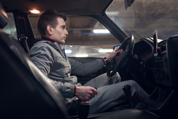 Photo from side of young man sitting in car