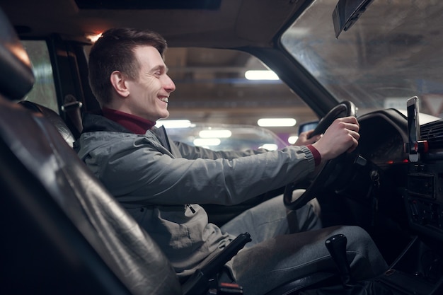 Photo from side of young smiling man sitting in car