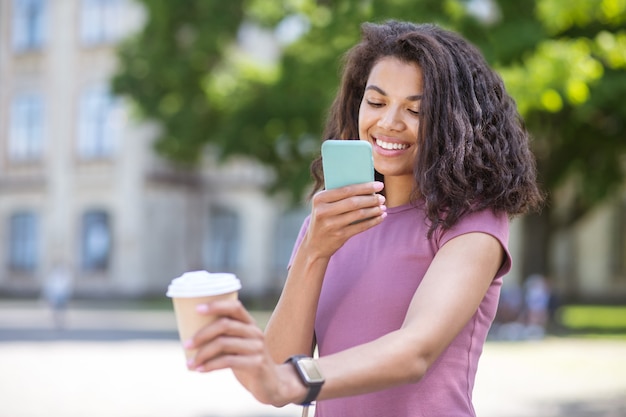 Photo. A girl making photo of a cup with coffee on a smartphone