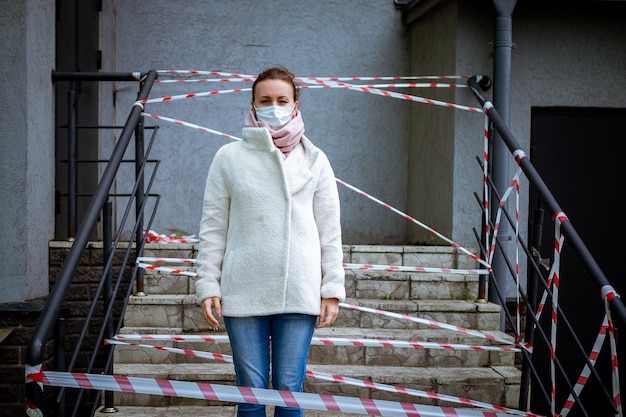 Photo of a girl in a mask Standing on the street with danger warning tapes