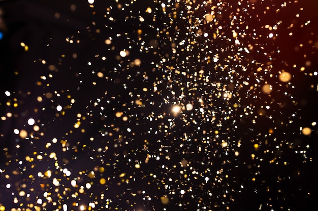 Photo of golden glitter on a black background. Golden explosion of confetti. Holiday background