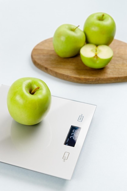 Photo of green apple on kitchen scales On background several apples on wooden board Healthy eating