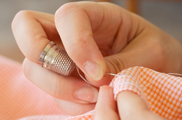 Photo of hands sewing with the focus in the thimble