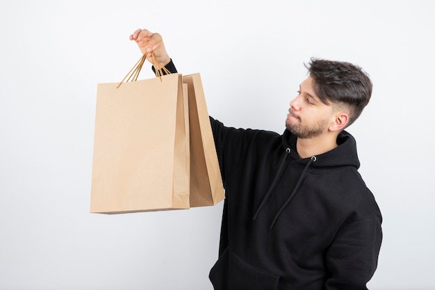 Photo of handsome man in black hoodie looking at craft bags