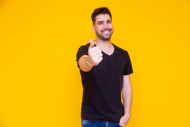 Photo of handsome man in casual t-shirt smiling on camera with thumb up.