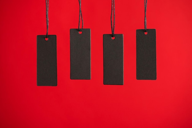 Photo of hanging black price tags on isolated red background with blank space