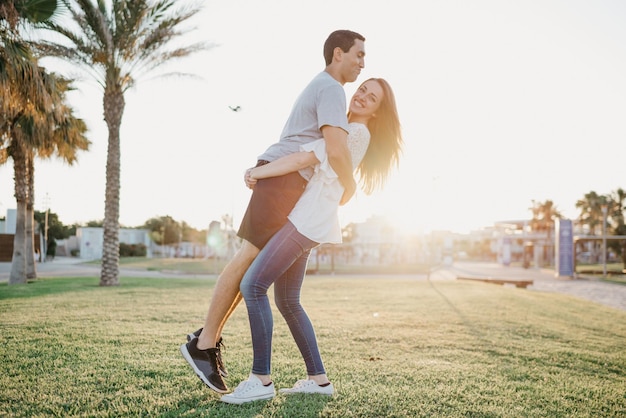 A photo of a happy brunette girl who is lifting her Hispanic boyfriend between palm trees