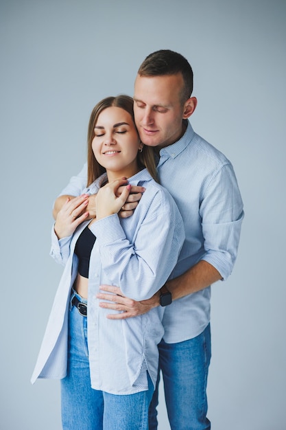 Photo of happy couple wearing white shirts blue jeans isolated white background A man and a woman are hugging on a white background