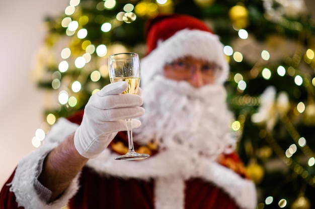 Photo of happy Santa Claus in eyeglasses holding a glass of champagne