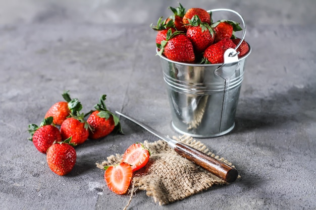 Photo of heap of fresh strawberries in the bowl on rustic grey background.
A bunch of ripe strawberries in a can bowl on the table. Copy space. Healthy fresh fruit. Organic food. Clear food