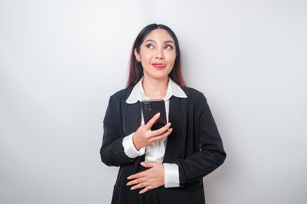 Photo of a hungry excited young businesswoman holding her phone and wondering what to order yummy food isolated on white color background