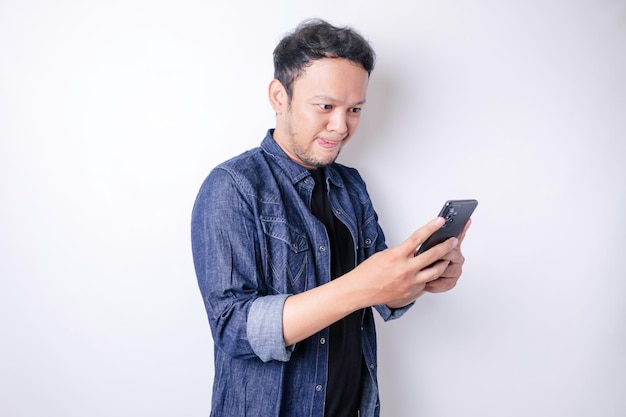 Photo of hungry excited young man look at his phone ordering yummy food isolated on white color background