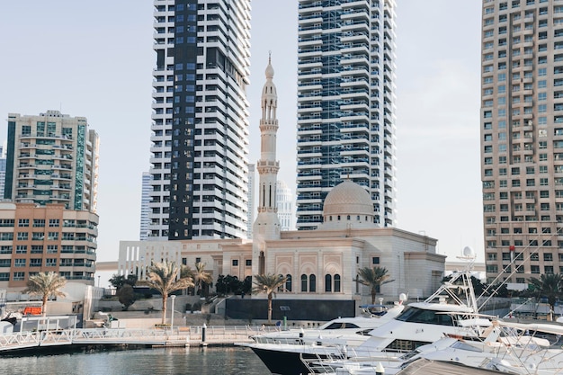 Photo of the imposing large Mohammed Bin Ahmed Al Mulla Mosque between the high rise buildings of the Dubai Marina on the Al Emreef Street bridge