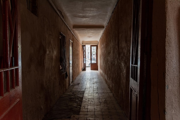 Photo inside the corridor of an old apartment building the sun shines through the windows and front door