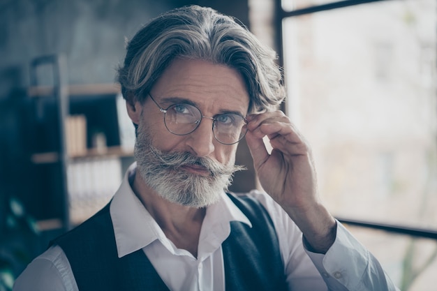 Photo of intellectual businessman touching specs in office