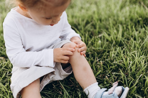 Photo of a little girl who fell and scratched his knee in the blood it hurts the wound