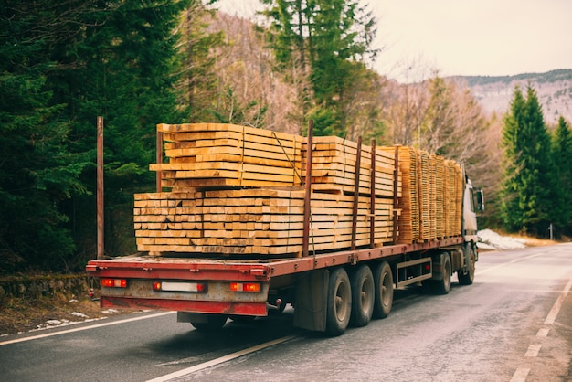 Photo photo of a long truck transporting wood on a road.