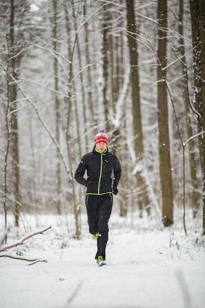 Photo of man in sportswear red cap on run in winter