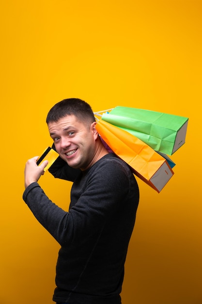 Photo of man with bank card and multicolored shopping bags