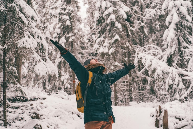 Photo of man with hands up for walk in winter forest