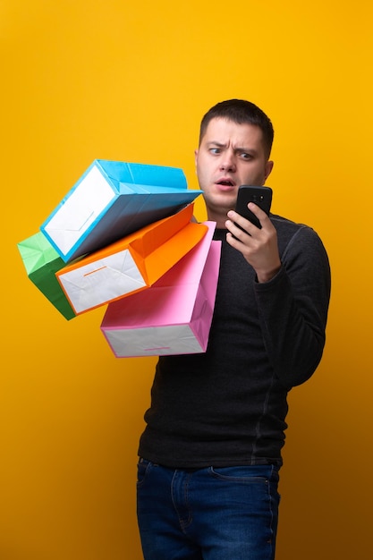 Photo of man with phone and multicolored shopping bags