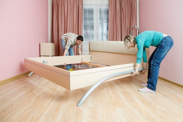 Photo of man and woman rearranging bed