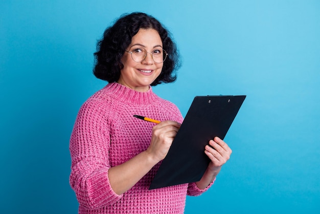 Photo of mature aged business woman concentrated keeping clipboard tablet reading isolated over pink color background