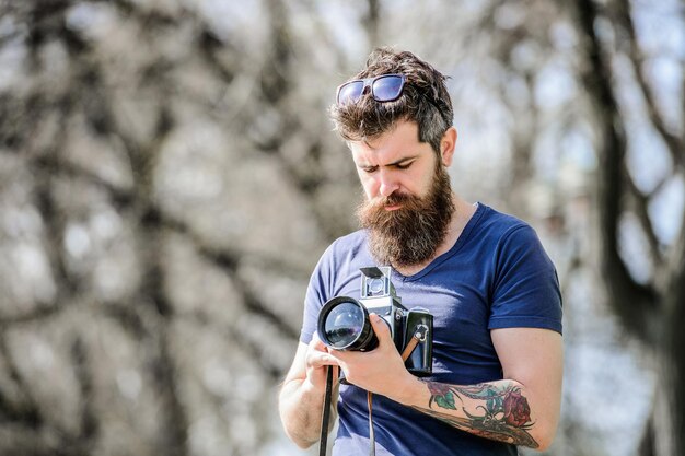 Photo of nature. reporter. Photographers choosing it. hipster man in summer sunglasses. retro photographic equipment. Mature hipster with beard. Bearded man. brutal photographer with camera.