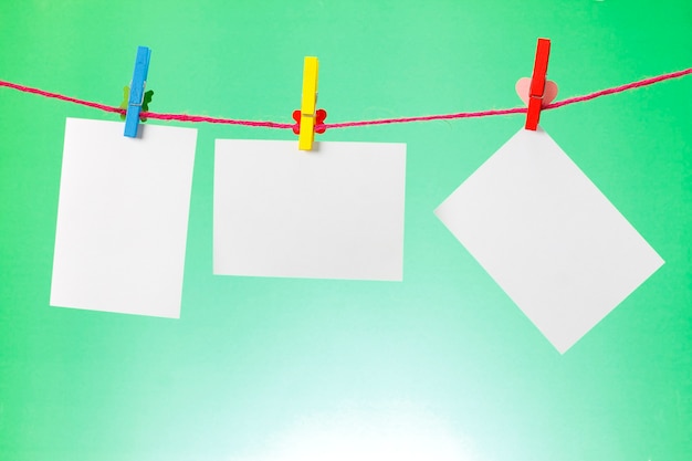 Photo paper hanging on the clothesline on light green background