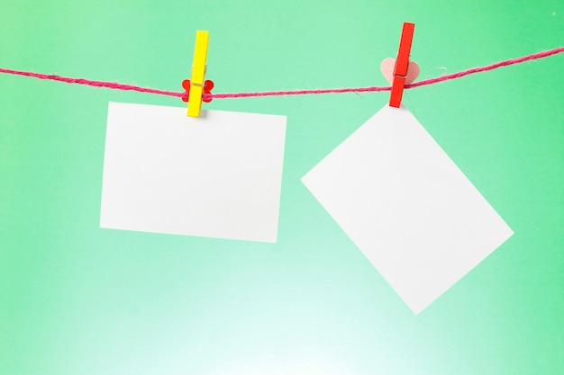 Photo paper hanging on the clothesline on light green background