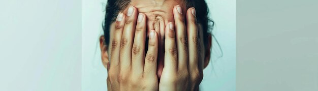 Photo photo of a person holding their face in their hands with their eyes closed set against a plain white background indicating deep emotional distress