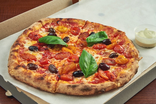 Photo for pizza delivery. Margarita pizza with cherry tomatoes, basil and mozzarella in a cardboard