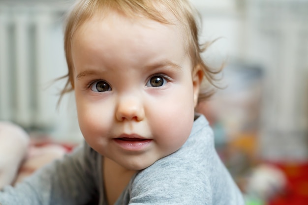 Photo portrait of a baby girl with pink cheeks. Baby gets to his feet